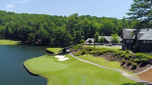 Un campo de golf con un obstáculo acuático, un búnker de arena y un club house.
