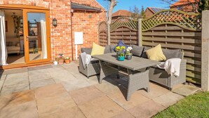 A patio with wicker furniture, a brick wall, and a wooden fence.