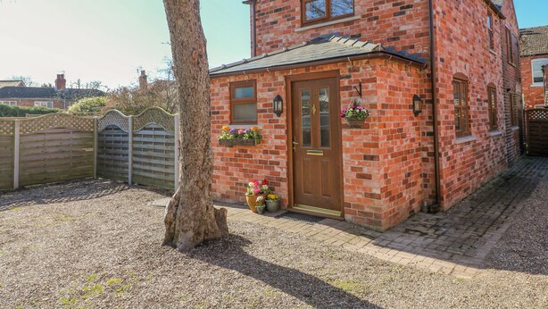 A brick house with a wooden door, a small porch, and a window with a flower box.