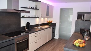 Una cucina moderna con forno integrato, macchina del caffè e una ciotola di frutta sul piano di lavoro.