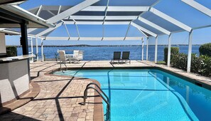 Zona de piscina con vistas al mar, un espacio de descanso techado y un bar junto a la piscina.