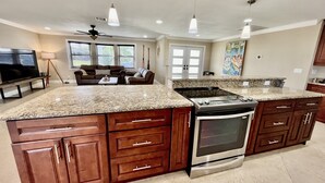 A spacious kitchen with granite countertops, wooden cabinets, and a stainless steel stove. - Stunning open water view 3 bedroom house, pool, private dock (Cape Coral)