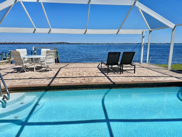 Zona de piscina con área de estar cubierta, piscina y vistas al mar.