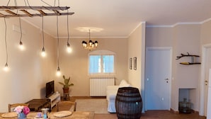 A spacious dining area with a wooden table and chairs, a chandelier, and a rustic barrel.