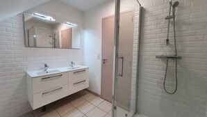 A modern bathroom with a white vanity, a glass shower enclosure, and a large mirror. - Gite Le Paradis (Lacave)