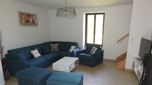 A modern living room with a sectional sofa, a white coffee table, and a blue armchair. - Gite Le Paradis (Lacave)
