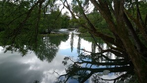 A serene lake surrounded by dense trees reflecting the sky. - Gite Le Paradis (Lacave)
