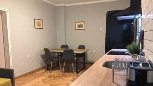 Ett kompakt kök med en träbänkskiva, en diskho och en matplats med stolar.