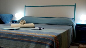 A neatly made bed with a striped bedspread, a rolled towel, and a folded towel on the bed. - LG Affittacamere Acireale (Acireale)