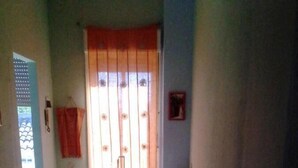 A staircase with a metal railing, leading to a landing with a window with orange curtains. - LG Affittacamere Acireale (Acireale)