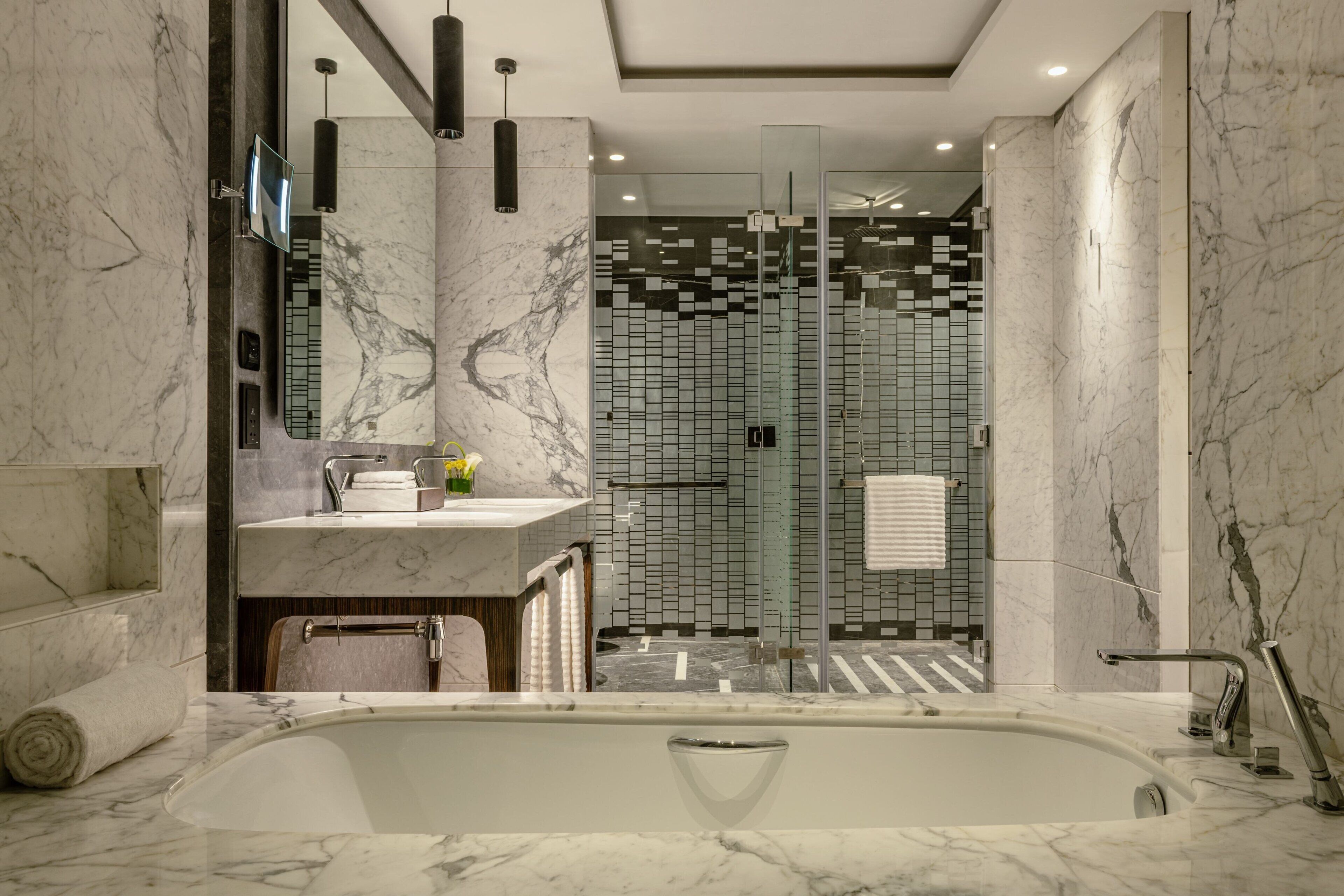 Un bagno moderno con lavabo in marmo, una vasca da bagno ampia e una zona doccia con pareti in vetro.