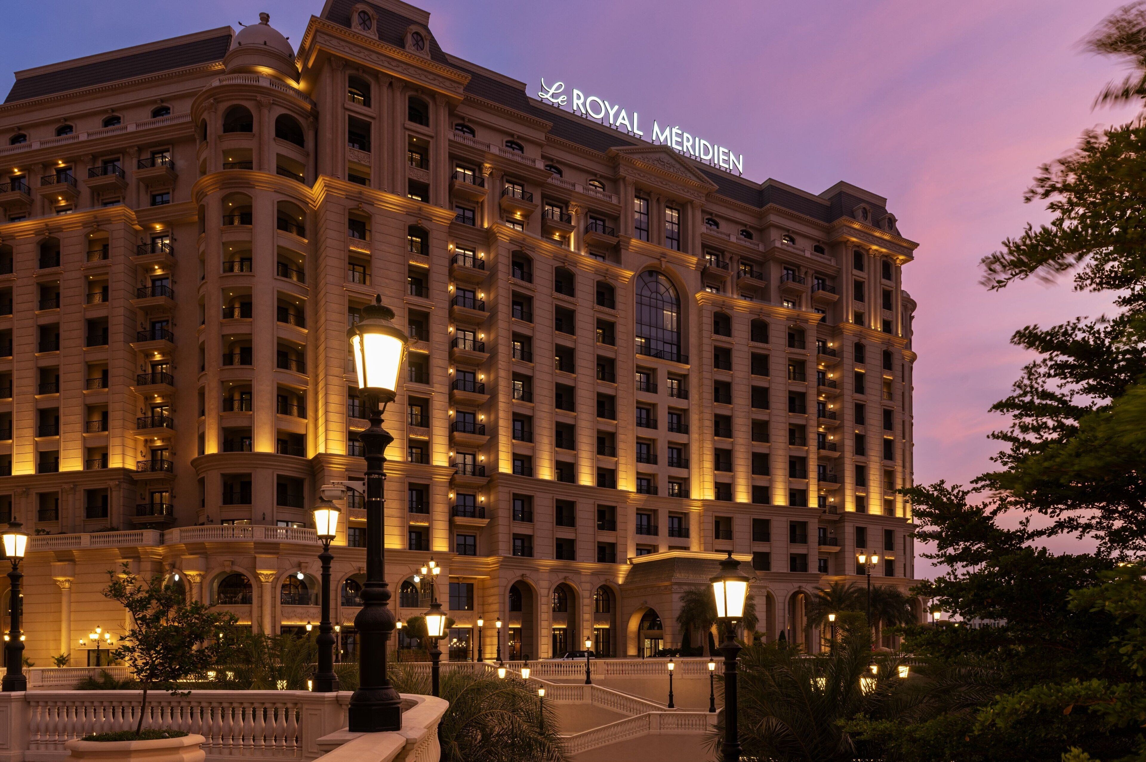 A large, multi-story hotel with a classic architectural style, featuring numerous balconies and a prominent sign at the top.