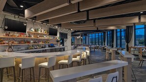 A modern bar area with a long counter, white bar stools, and a variety of bottles on shelves. - Element by Marriott Colorado Springs Downtown (Colorado Springs)