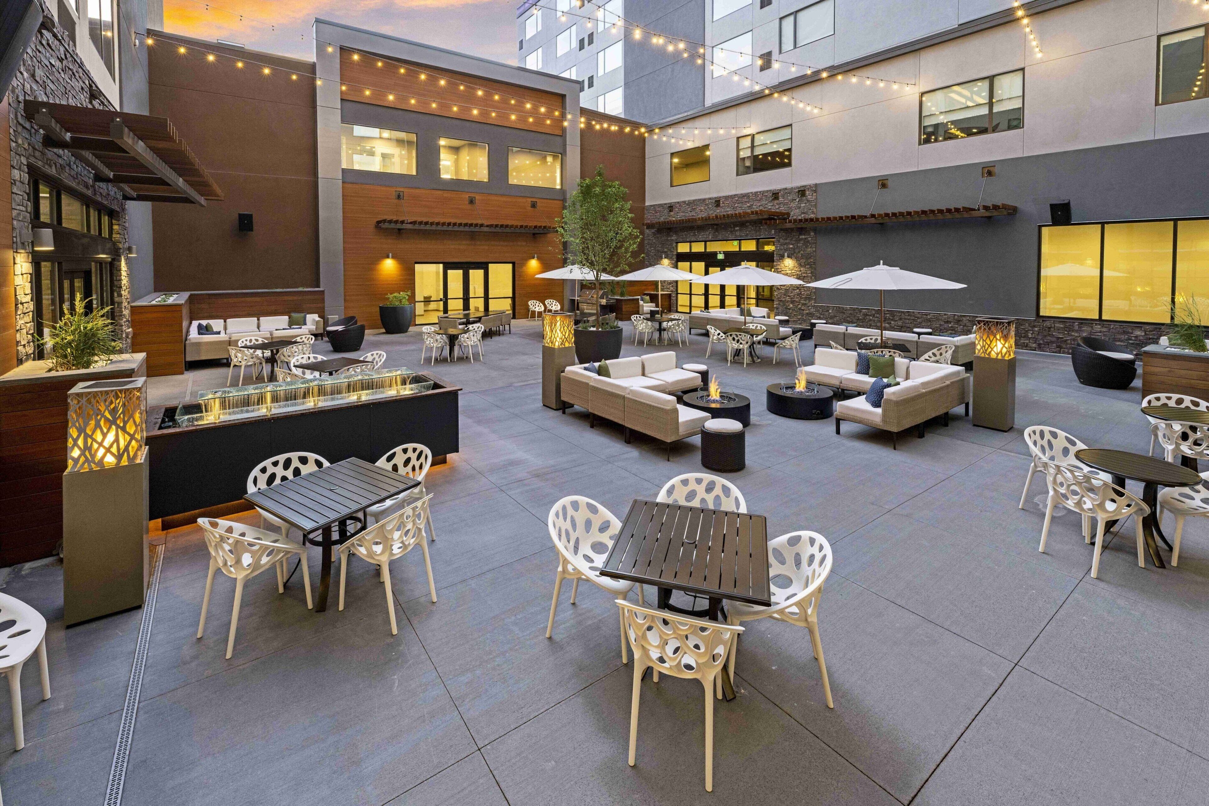 An outdoor patio area with seating arrangements, tables, and umbrellas.