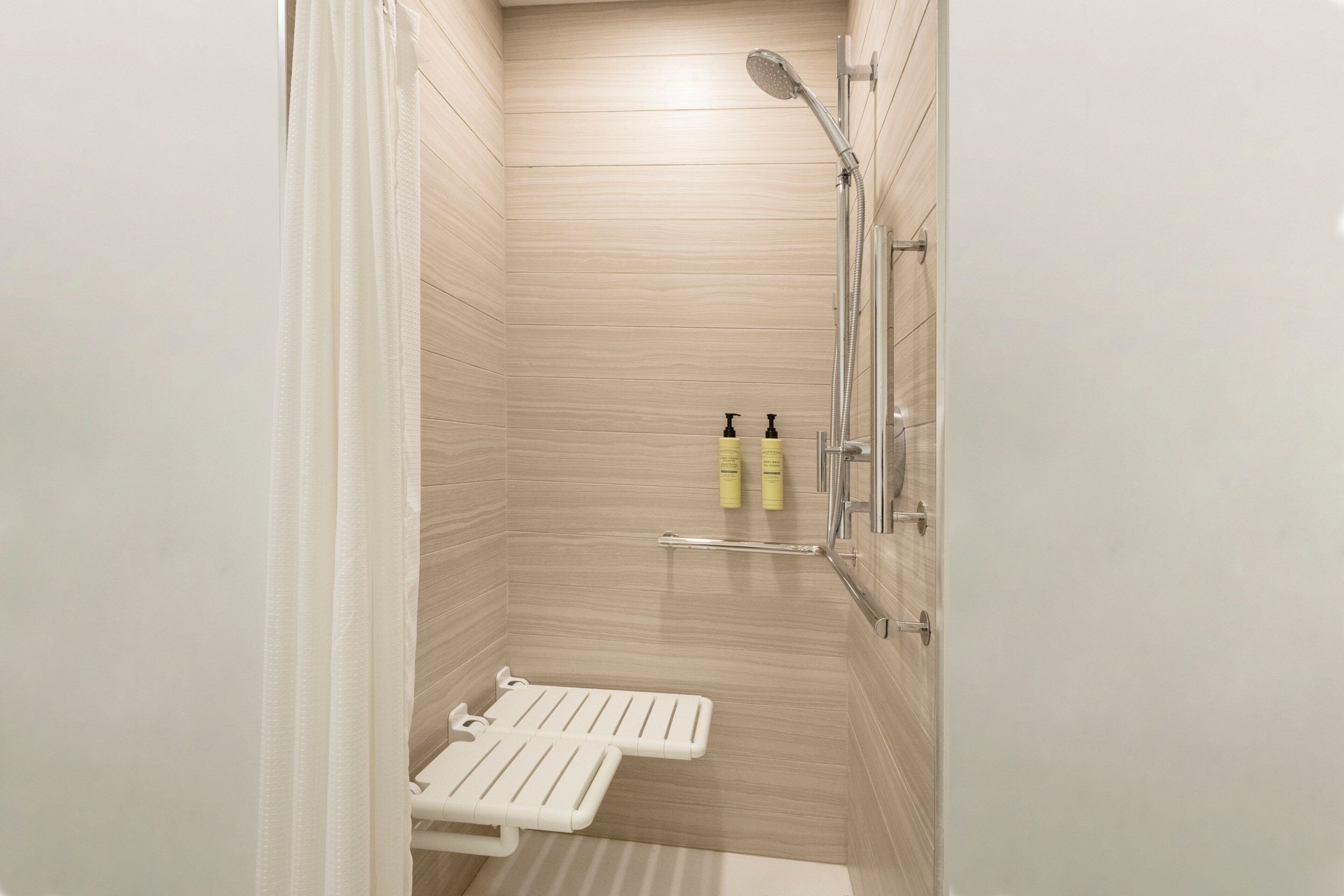 A small, modern bathroom with a shower, a toilet, and a bench.