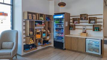 A modern interior with wooden shelves displaying snacks and beverages, a seating area, and a refrigerator.