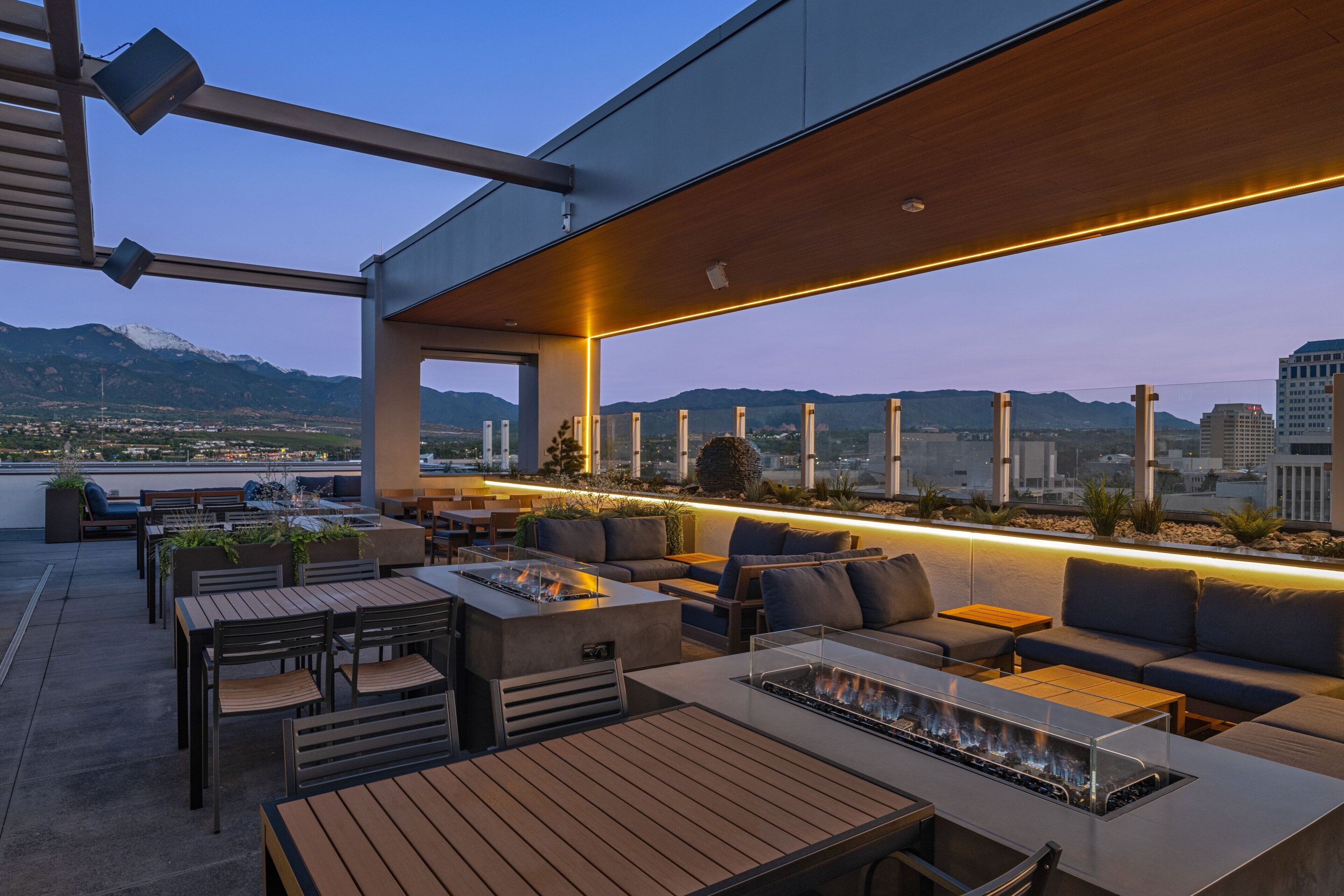 Una terrazza sul tetto con posti a sedere all'aperto, un braciere e vista sulla città e sulle montagne.