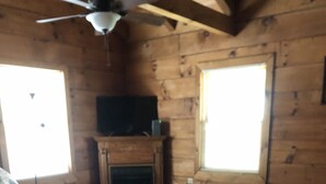A wooden cabin interior with a fireplace, a sofa, a coffee table, and a lamp. - Cabin #4   Secluded and Quiet (Oneida)