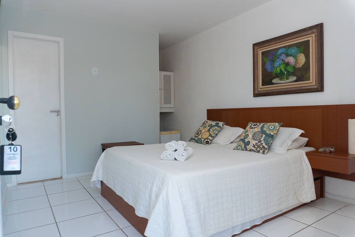 A neatly made bed with white bedding, a wooden headboard, and decorative pillows.