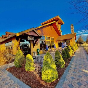 A lodge with a large entrance, outdoor seating, and neatly trimmed bushes. - Juniper Ridge Chalet at Eagle Crest Resort (Redmond)