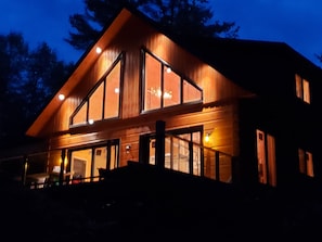 A large, modern wooden house with multiple large windows and a prominent gable roof.