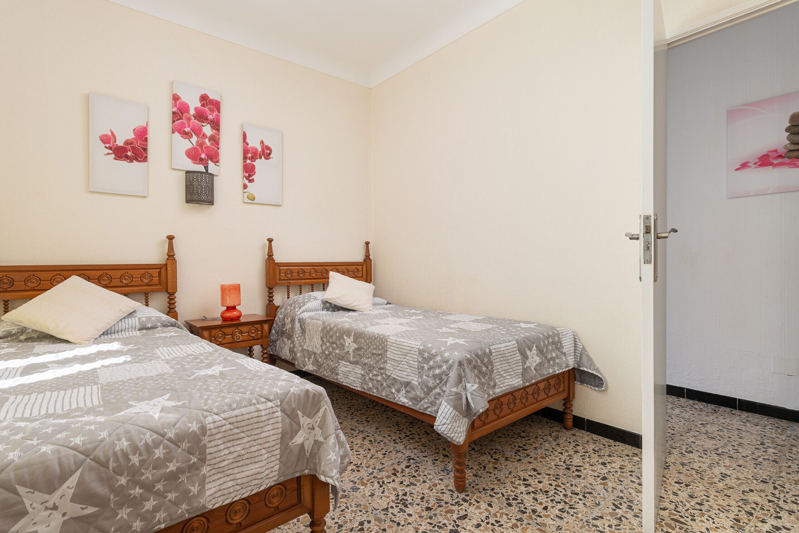 A bedroom with two wooden beds, a nightstand, and a door.