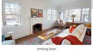 Una sala de estar con chimenea, ventanas amplias y un sofá.