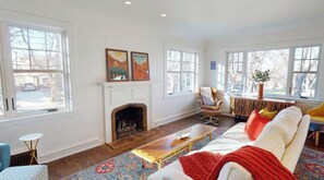 A living room with a fireplace, large windows, and a sofa.