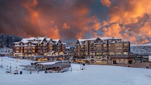 Un grand chalet à plusieurs étages, avec un télésiège visible au premier plan.