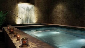 Un espace de bien-être comprenant une piscine, une cascade et un éclairage à la bougie.