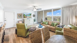 A spacious living room with a sofa, chairs, a coffee table, and a dining area. - Sandcastle Condominiums Unit 113 (Port Aransas)