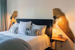 A neatly made bed with a dark headboard, multiple pillows, and a bedside table with a lamp and a tissue box. - Sleepy Hollow Retreat with Hot Tub + Barrel Sauna (Allenspark)