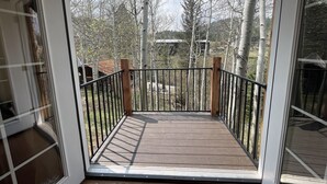 Eine Holzterrasse mit Metallgeländer, das zu einer Glastür führt.