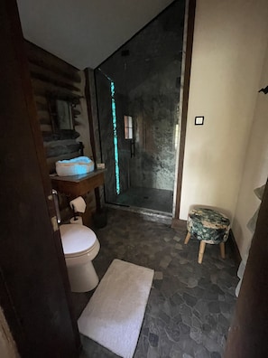 A bathroom with a toilet, sink, and a small stool.