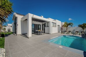 A modern house with a swimming pool, a patio with chairs, and a table. - ORCADES VILLA NEAR DOWNTOWN WITH SWIMMING POOL & AIR CONDITIONING (Playa Blanca)