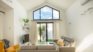 A modern living room with a large window, a flat-screen TV, a sofa, and a coffee table. - VILLA ORCADES CLOSE TO TOWN CENTER POOL & A/C (Playa Blanca)