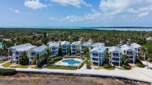 A resort with multiple buildings, a swimming pool, and a view of the ocean.