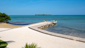 A beach with a clear blue sky, a sandy area, and a small island in the distance.