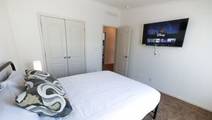 A bedroom with a bed, a television mounted on the wall, and a door leading to another room.