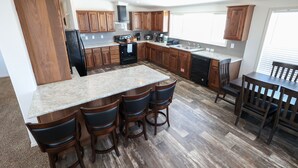A modern kitchen with wooden cabinets, a granite countertop, and a bar area with stools.