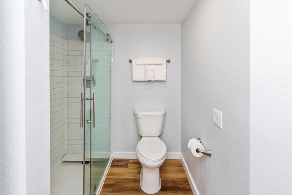 A modern bathroom with a glass shower enclosure, a white toilet, and a towel rack.