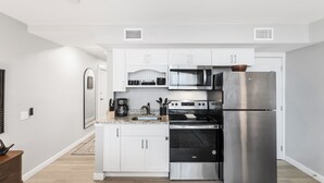 Een moderne keuken met witte kasten, roestvrijstalen apparatuur en een houten vloer.
