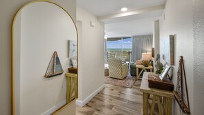 A spacious living room with a view of the ocean, a large mirror, and a wooden floor. - Sandcastle Condominiums Unit 213 (Port Aransas)