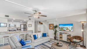 A modern living room with a sofa, armchairs, a coffee table, and a TV. - Sandcastle Condominiums Unit 225 (Port Aransas)