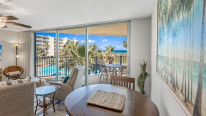 A hotel room with a balcony, a pool view, and a painting of a beach scene. - Sandcastle Condominiums Unit 225 (Port Aransas)