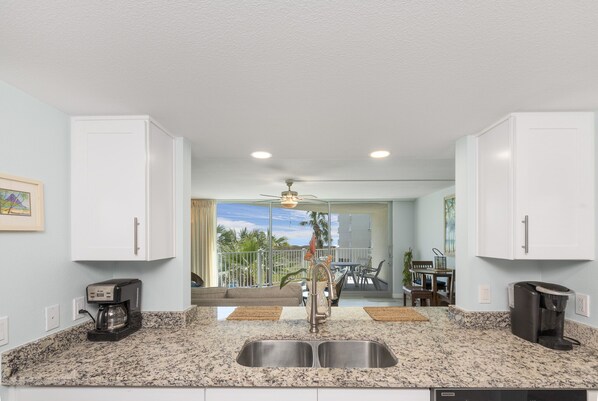 A kitchen with granite countertops, a double sink, and a coffee maker.