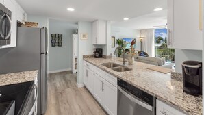 A modern kitchen with white cabinets, granite countertops, and stainless steel appliances. - Sandcastle Condominiums Unit 225 (Port Aransas)