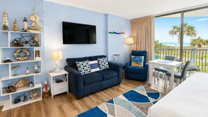 Une pièce avec un canapé, un fauteuil, une télévision et une vue sur l’océan.