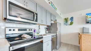 A modern kitchen with stainless steel appliances, white cabinetry, and a wooden countertop.