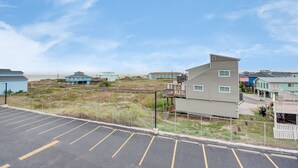 A coastal residential area with a parking lot, beachfront properties, and a clear sky.